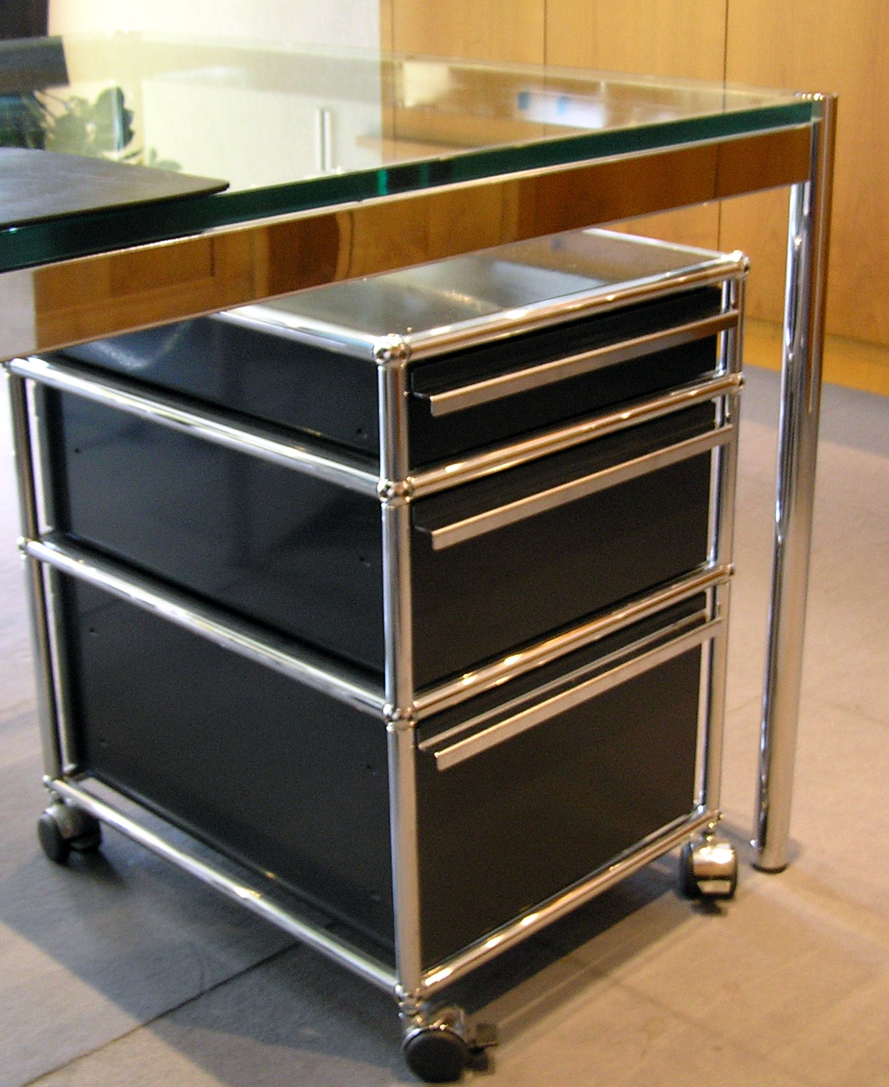 Schwarzer Haller-Schubladencontainer mit sichtbaren verchromten Kugeln und Rohren unter einem Glastisch