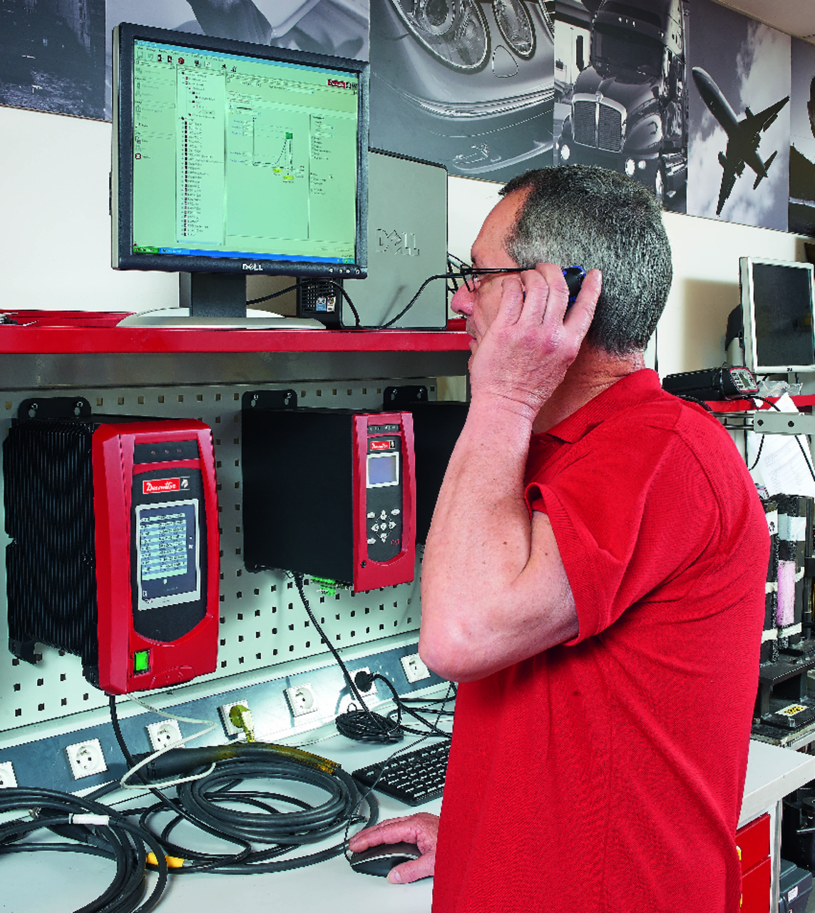 Ein Servicetechniker telefoniert an einem Arbeitsplatz mit Desoutter-Steuerungen und Bildschirm