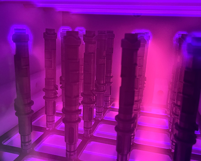 Metallische Fahrradkomponenten in einer violett leuchtenden Plasmakammer.