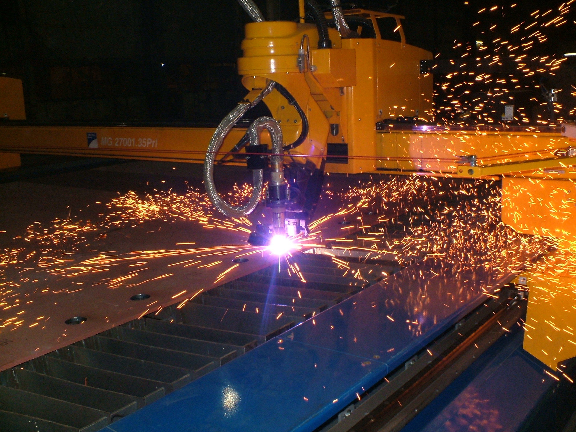 Zwei Schneidköpfe einer CNC-Plasmaschneidanlage über einem Metallblech mit sichtbarem Funkenflug.